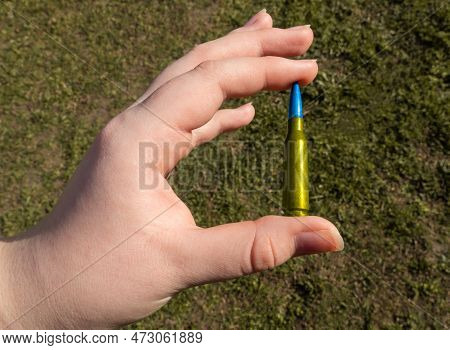 Yellow-blue Rifle Cartridge In Hand Against The Background Of Green Grass (national Symbols Of Ukrai