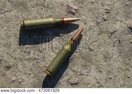 Two Rifle Cartridges Lie On A Concrete Surface (close-up)