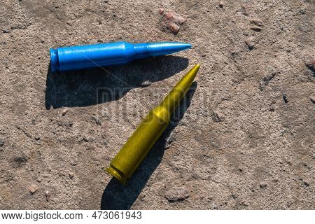 Yellow And Blue Rifle Cartridges (the National Symbol Of Ukraine) Lie On A Concrete Surface (close-u