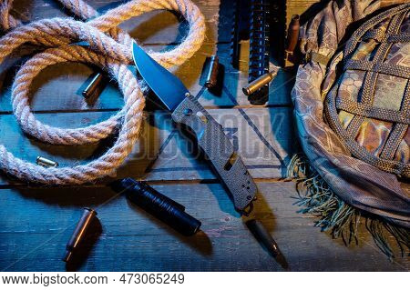 Military Composition With A Knife And A Rope. Rope And Sleeves On A Military Box. Warm Yellow Light.
