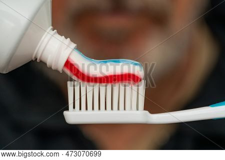 Squeezing Colored Toothpaste Onto A Toothbrush. Close Up.