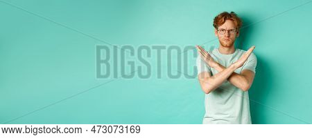 Serious And Confident Redhead Man In T-shirt And Glasses Saying No, Showing Cross Gesture To Stop Yo