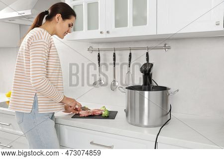 Woman Cutting Meat Near Pot With Sous Vide Cooker In Kitchen. Thermal Immersion Circulator