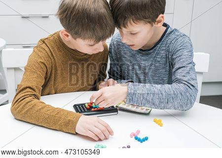 Two Pensive And Enthusiastic Boys Playing Educational, Strategy Board Game With Black Field And Colo