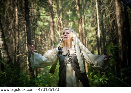 Adult Mature Woman 40-60 In A Green Long Fairy Dress In Forest. Photo Shoot In Style Of Dryad And Qu
