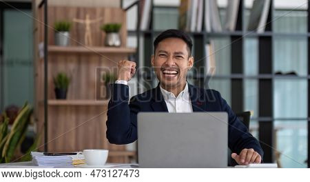 Happy Young Businessman Looking At Laptop Computer In Office, Excited Asian Man Working At His Workp