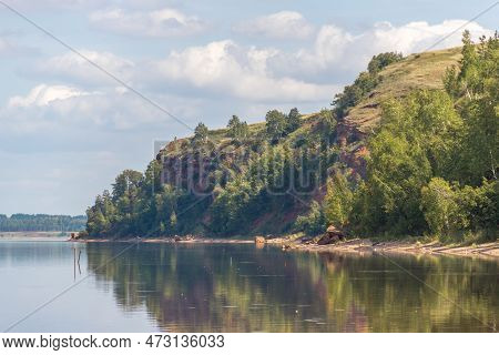 Lake Surrounded By Green Forest, Red Hill With Forest On Background