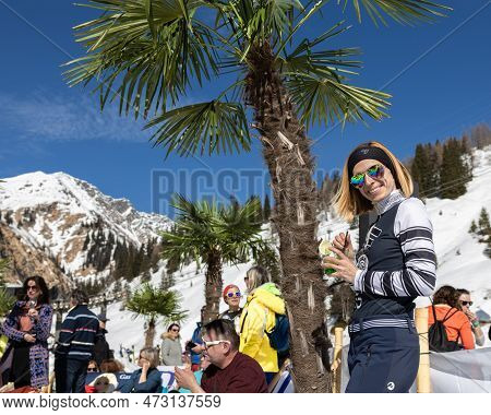 Austria, Sportgastein - March 18, 2023: Event Palmen Auf Den Almen, Young Woman Posing Against The B