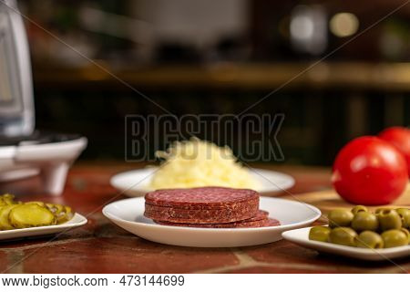 Salami On A Plate Close-up. Various Ingredients For Making Pizza.