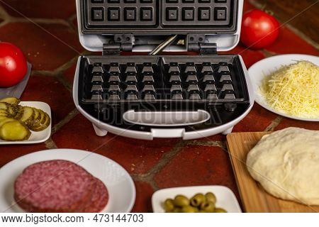 Cooking Pizza Waffle, Piffle. Different Ingredients - Sausage, Olives, Pickles, Dough On The Kitchen