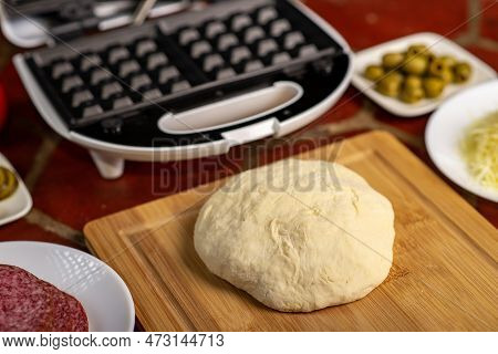 Cooking Pizza Waffle, Piffle. Different Ingredients - Sausage, Olives, Pickles, Dough On The Kitchen
