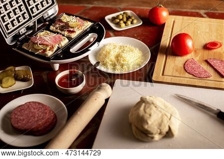 Cooking Waffles Stuffed With Sausage, Cheese. Pizza Waffle, Piffle. Various Ingredients On The Kitch