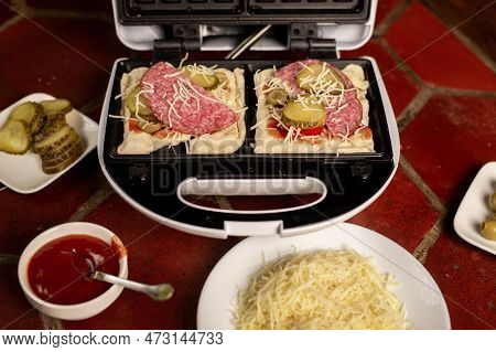 Cooking Pizza Waffle, Piffle. Waffle Iron And Different Ingredients On The Kitchen Table.