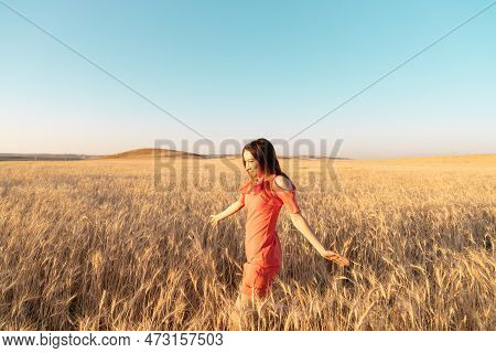Young Woman In The Wheat Field. Connecting With Nature Concept. Moments Of Joy. Arms Out To The Side
