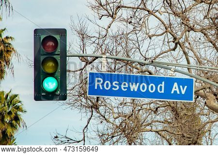 Street Name Rosewood Avenue In Hollywood With Red Traffic Light Under Cloudy Sky
