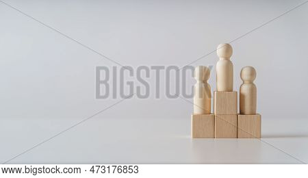 Wooden Figures Peg Doll Standing On The Podium Of Wooden Cube Blocks With Copy Space. Ranking And St