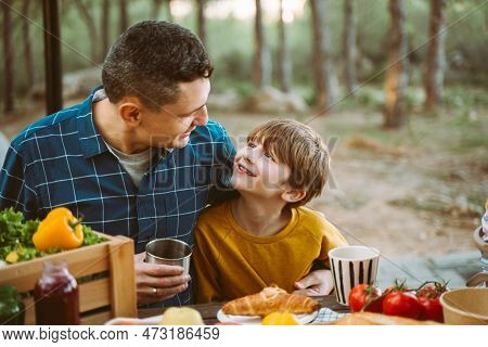Father Hugs His School Boy Son On A Family Picnic In Mountains Forest Park. Child Kid And His Dad Ta
