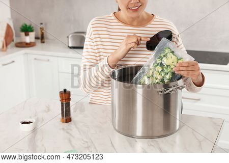 Woman Putting Vacuum Packed Broccoli Into Pot And Using Thermal Immersion Circulator, Closeup. Sous 