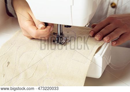 Cropped Woman Dressmaker Hands Using Sewing Machine, Putting White Soft Fabric With Stitch Contour O