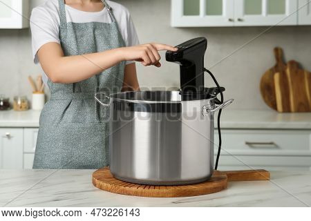 Woman Using Thermal Immersion Circulator At Table In Kitchen, Closeup. Sous Vide Cooking