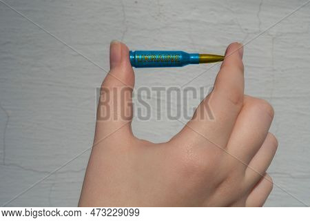 Yellow-blue Rifle Cartridge With The Inscription Ukraine In Hand Against A White Wall (national Symb