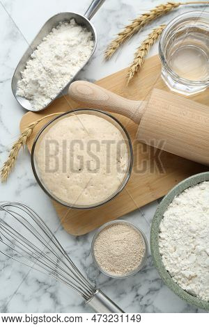 Leaven, Flour, Ears Of Wheat, Rolling Pin, Whisk And Water On White Marble Table, Flat Lay