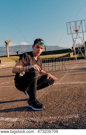 Portrait Of White Teenage Boy With Blue Hair Crouching On A Basketball Court. B-boy Dancer. Youth Cu