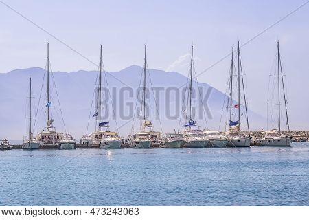Several Yachts Moored In One Row In A Light Morning Haze Against The Backdrop Of A Mountain In The P