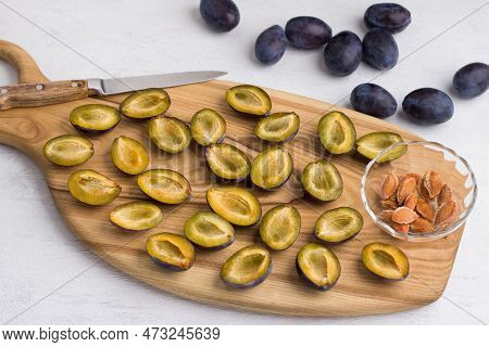 Wooden Board With Chopped And Peeled Plums, Halves Of Plums, A Bowl With Pits, Whole Plums And A Kit