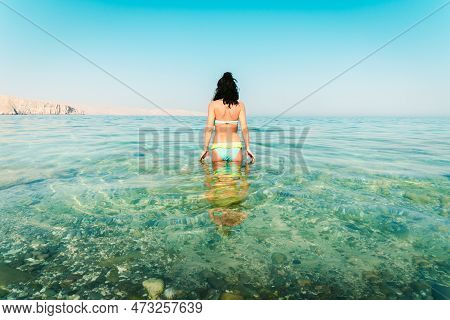 Back View Pretty Tourist Woman Stand In Clear Turquoise Water In Persian Gulf Mirellas Island. Oman 