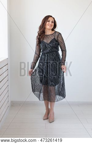 Attractive Woman With Long Brunette Hair Dressed In Fashionable Black Dress Smiling And Posing. Laug