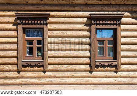 Russian Traditional Wooden Architecture. Windows Of Wooden House Decorated With Wooden Carvings, Pla