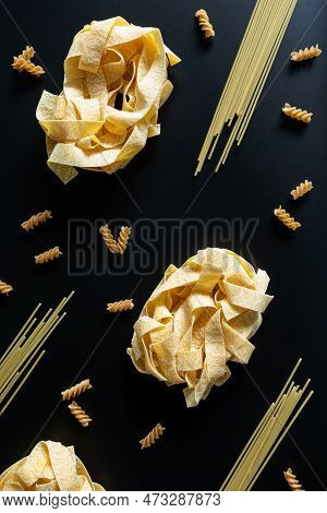 Different Types Of Uncooked Dried Pasta On The Black Background. Raw Pappardelle, Spaghetti And Fusi