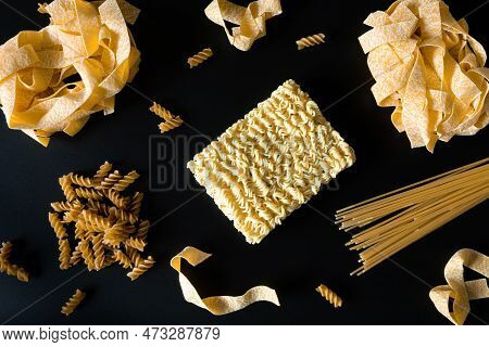 Different Types Of Uncooked Dried Pasta On The Black Background. Raw Pappardelle, Spaghetti And Fusi