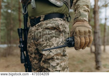 A Military Man In A Camouflage Uniform And Tactical Gloves Holds A Walkie-talkie.