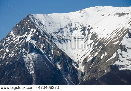 View Of Majestic Peak Of Mount Vettore Covered By Snow In The Marghe Region Against The Blue Sky, It