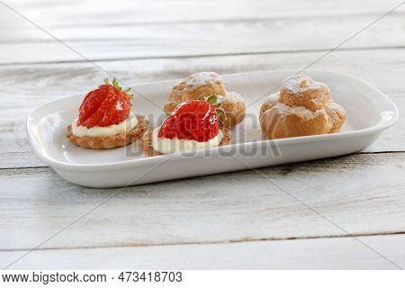 A Plate Of Strawberry Tarts And Cream Puffs Pasteries.