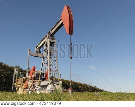 Operating Oil And Gas Well In Oil Field, Profiled Against The Blue Sky.