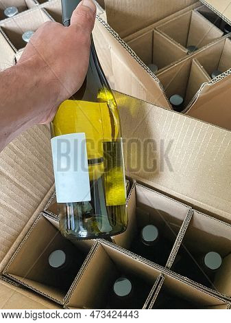 A Person Is Un Packing A Bottle Of Wine Ordered On The Internet Out Of A Delivery Box