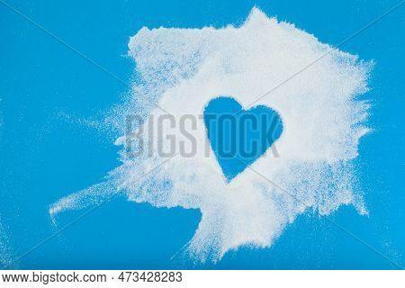 White Powder Is Chaotically Scattered On Blue Surface. Empty Space In The Form Of Heart. Collagen Or