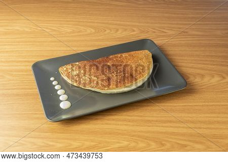 Image Of Venezuelan Corn Cachapa Stuffed With Cheese On Black Plate And 45 Degree View