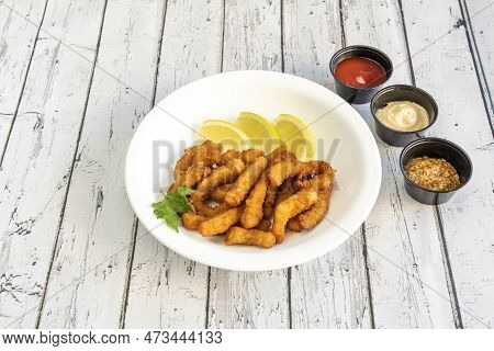 Great Serving Of Squid Rabas In Batter And Fried With Lemon Slices To Garnish And Sauces To Dip In A