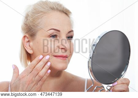 Happy Middle Aged Woman Model Touching Face Skin Looking In Mirror. Smiling Mature Older Lady Enjoyi
