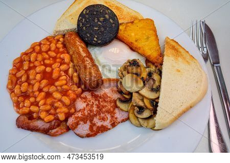 White Board With Full English Breakfast With Bacon, Fried Egg, Beans, Tomato, Roasted Sausage, Black