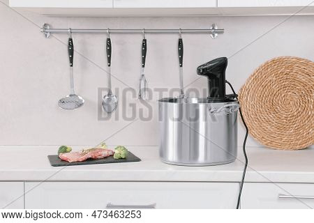 Pot With Sous Vide Cooker And Ingredients On Table In Kitchen. Thermal Immersion Circulator