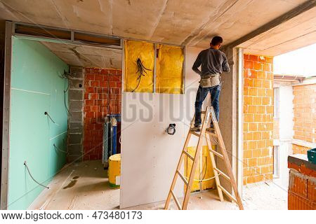 Repairman On Wooden Ladder Holds Professional Manual Power Tool Acu Drill And Tightens The Screws On