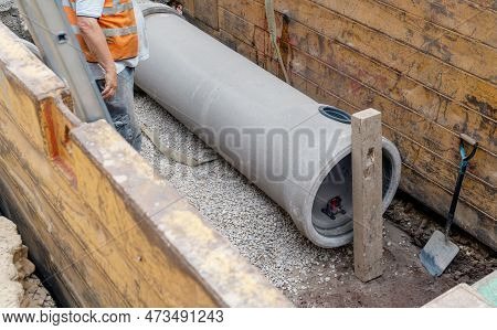 Builder Installing Big Diameter Concrete Drainage Pipe Protected By Trench Support System During Dee