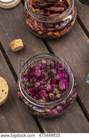 Glass Jar With Cork Lids Filled With Dried Tea Roses On Unvarnished Dark Wood Planks