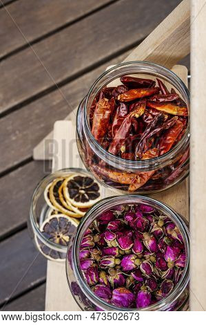 Top View Image Of A Glass Jar Filled With Dried Tea Roses And Another With Dried Chili Peppers On Un