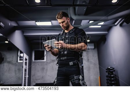 Focus On Training And Reading The Ems Training Results On The Tablet. A Young Attractive Man With Ma